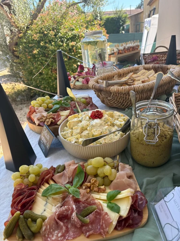 Buffet de réception en extérieur : planches de charcuterie et fromages, salade de pommes de terre et corbeilles de pain