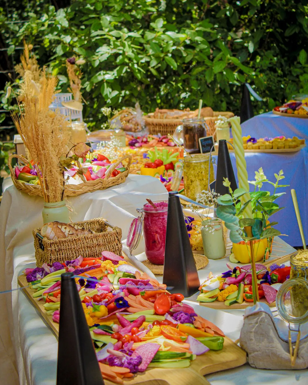 Buffet champêtre dressé en extérieur : planches de crudités colorées, verrines et pains
