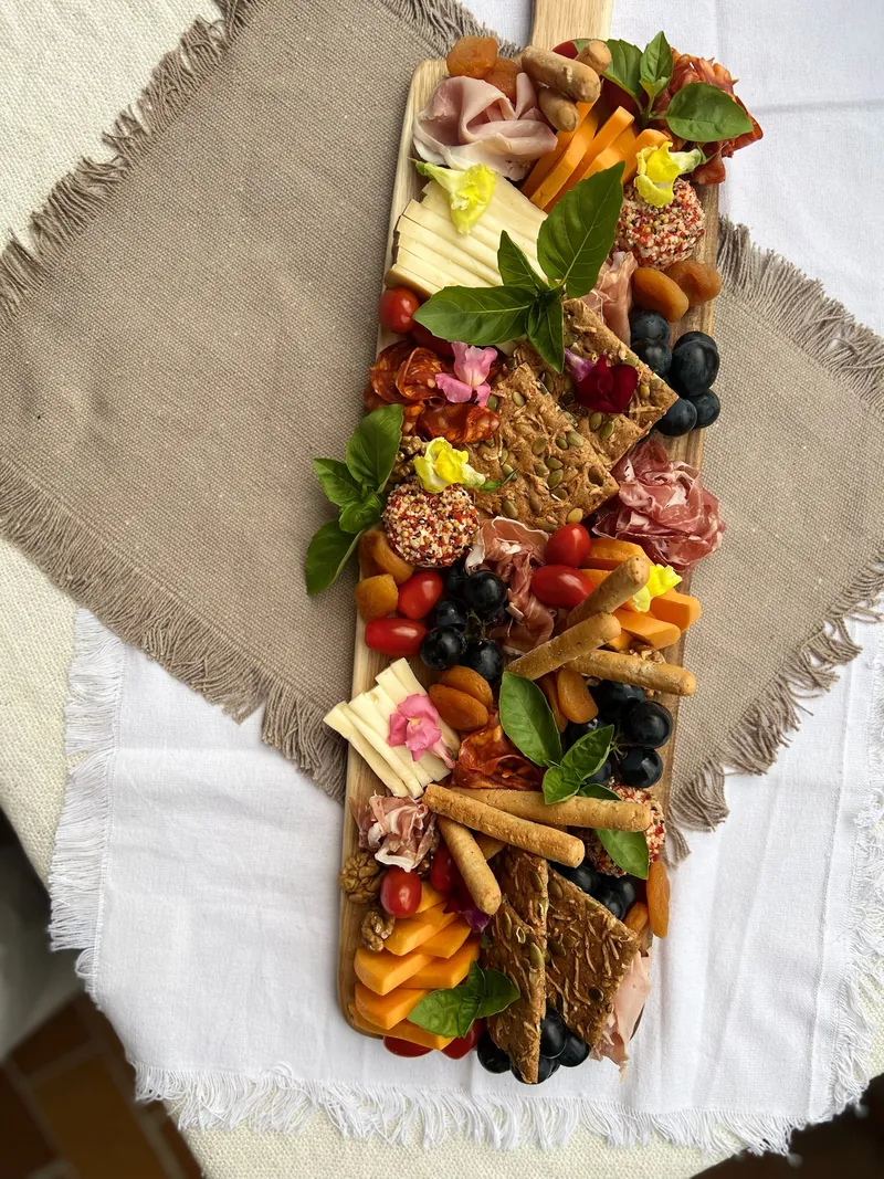 Longue planche de charcuterie et de fromages dressée sur une nappe de lin